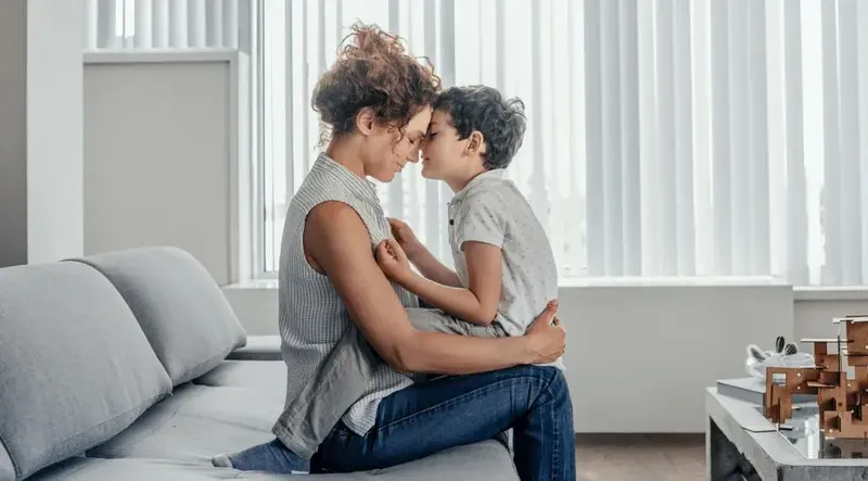 Woman touching foreheads with the child sitting in her lap